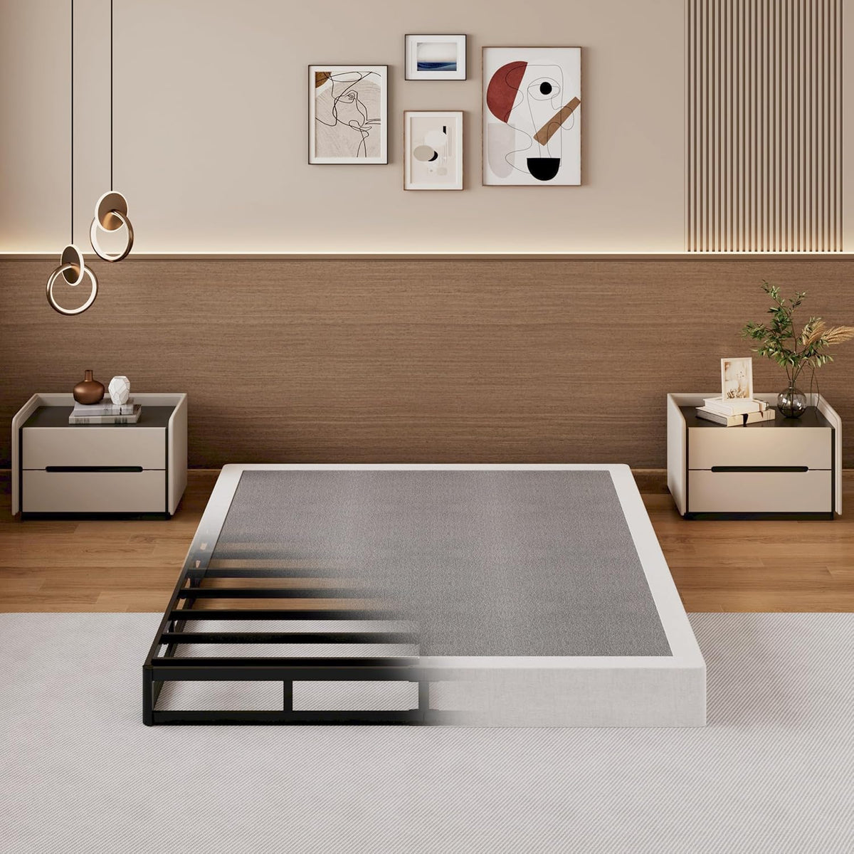 Low-angle front view showing black slatted bunkie board half revealed beside a white mattress outline in a styled bedroom.