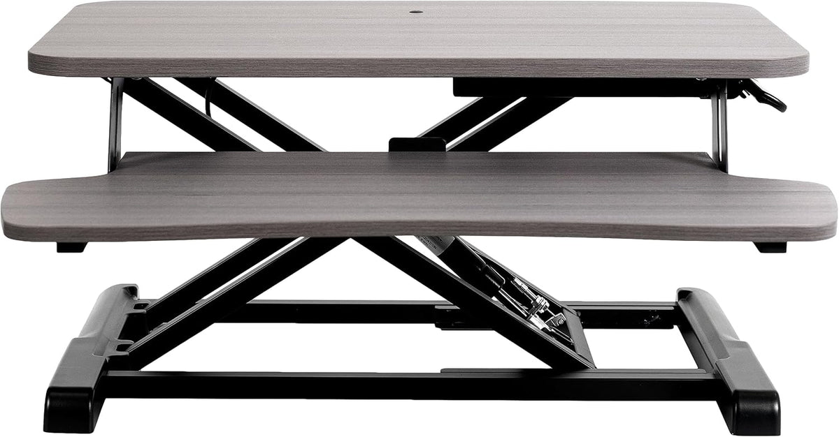 Front view of a gray-top standing desk converter with black metal base and X-frame lift.