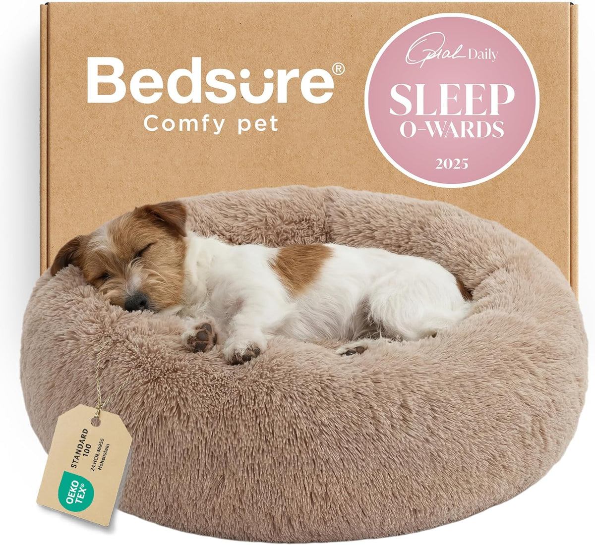 Front three-quarter view of a tan faux-fur donut bed with a small white-and-brown dog sleeping and a hanging tag.