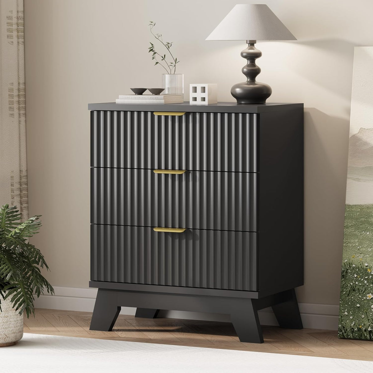 Closer side view of a black three-drawer chest with ribbed front panels and gold handles.