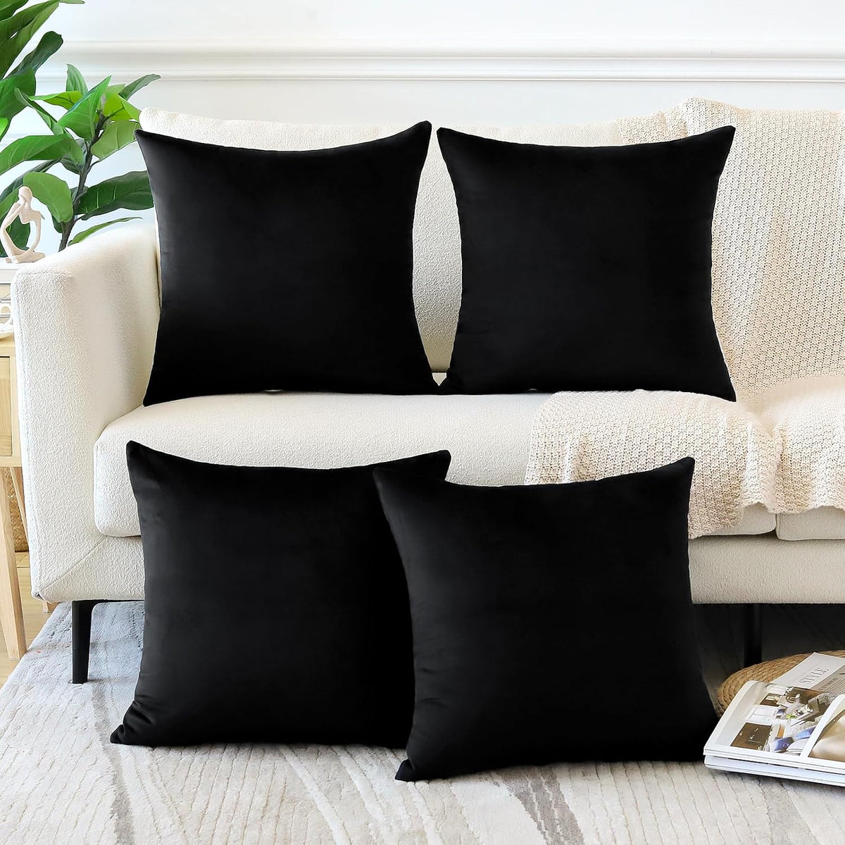 Four square black velvet throw pillow covers arranged on a cream sofa and rug.