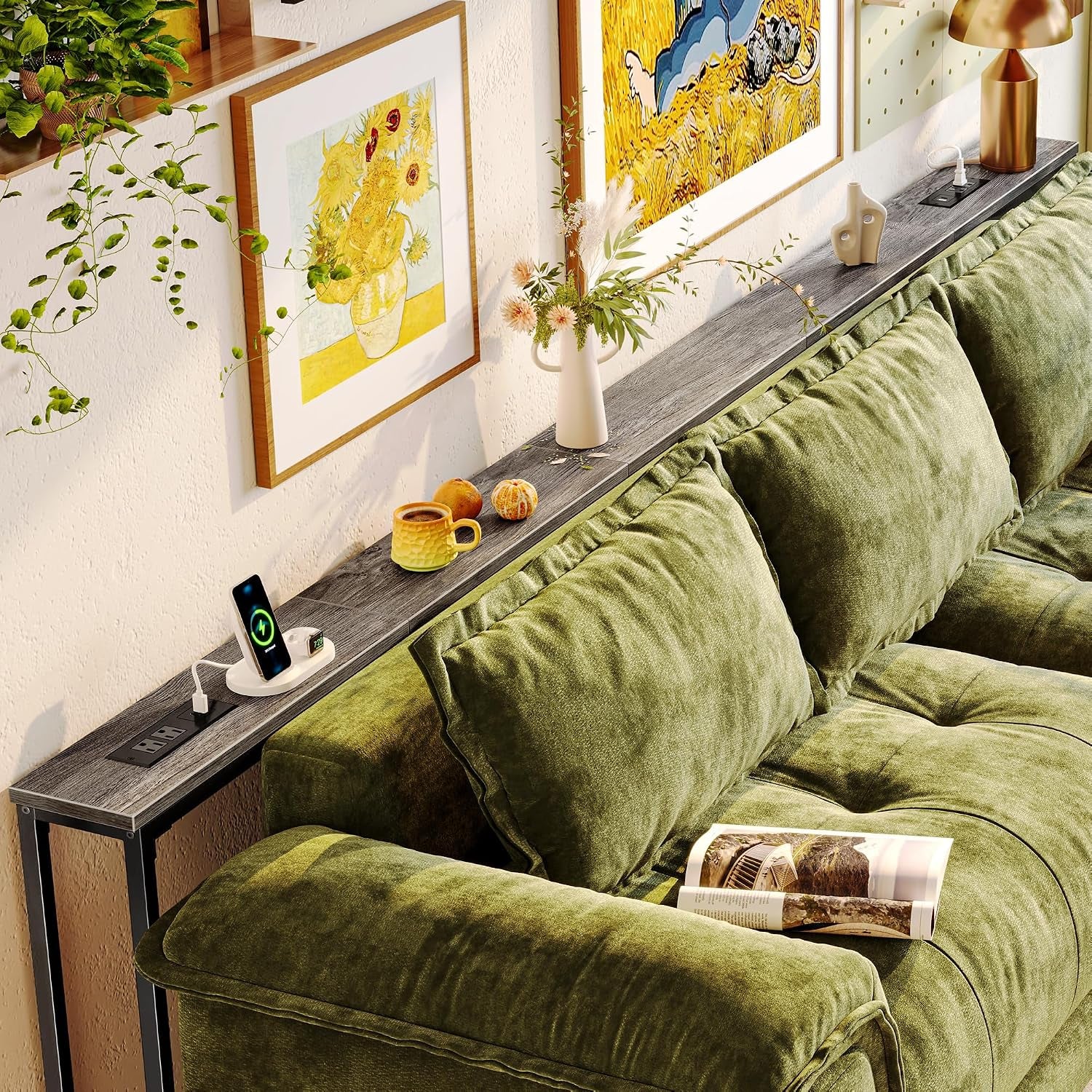 Extra-long skinny sofa table behind plush green cushions holding a lamp, vase and phone charger
