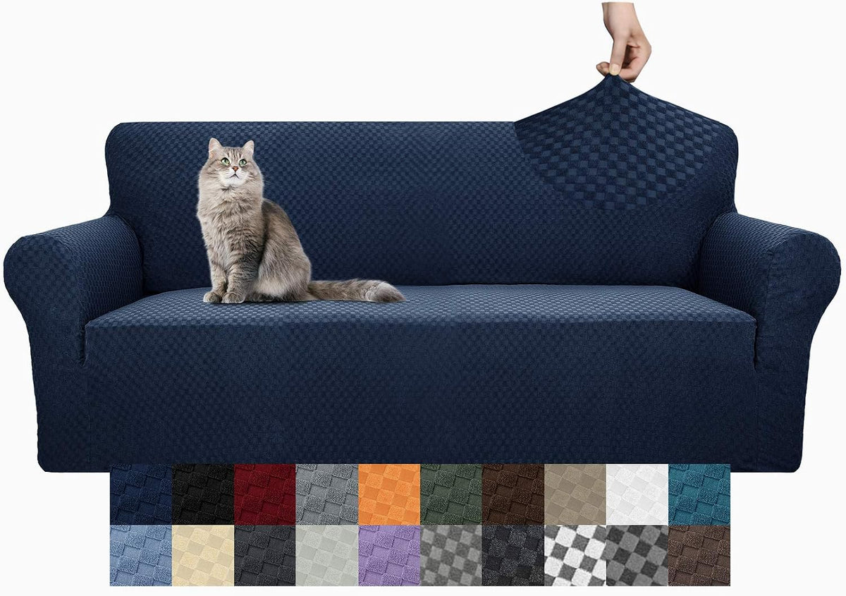 Deep navy stretch sofa cover on a three-seat couch with a seated gray cat and a hand pinching the back fabric; color tiles