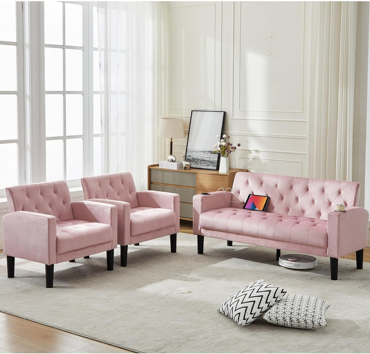 Pink tufted loveseat and two armchairs arranged by a dresser, tablet charging on the seat and patterned floor pillows nearby.