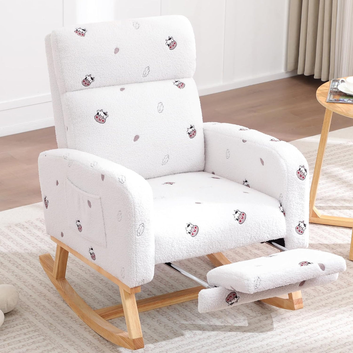 White patterned glider chair with tiny cow-face print and extended padded footrest on natural wood rockers