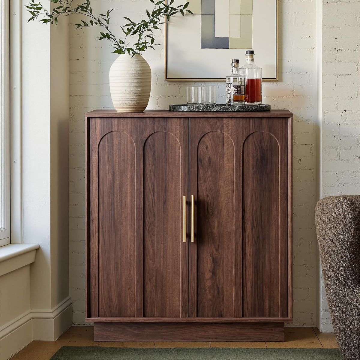 Styled living room view of walnut cabinet with vase on top and closed arched doors with gold handles