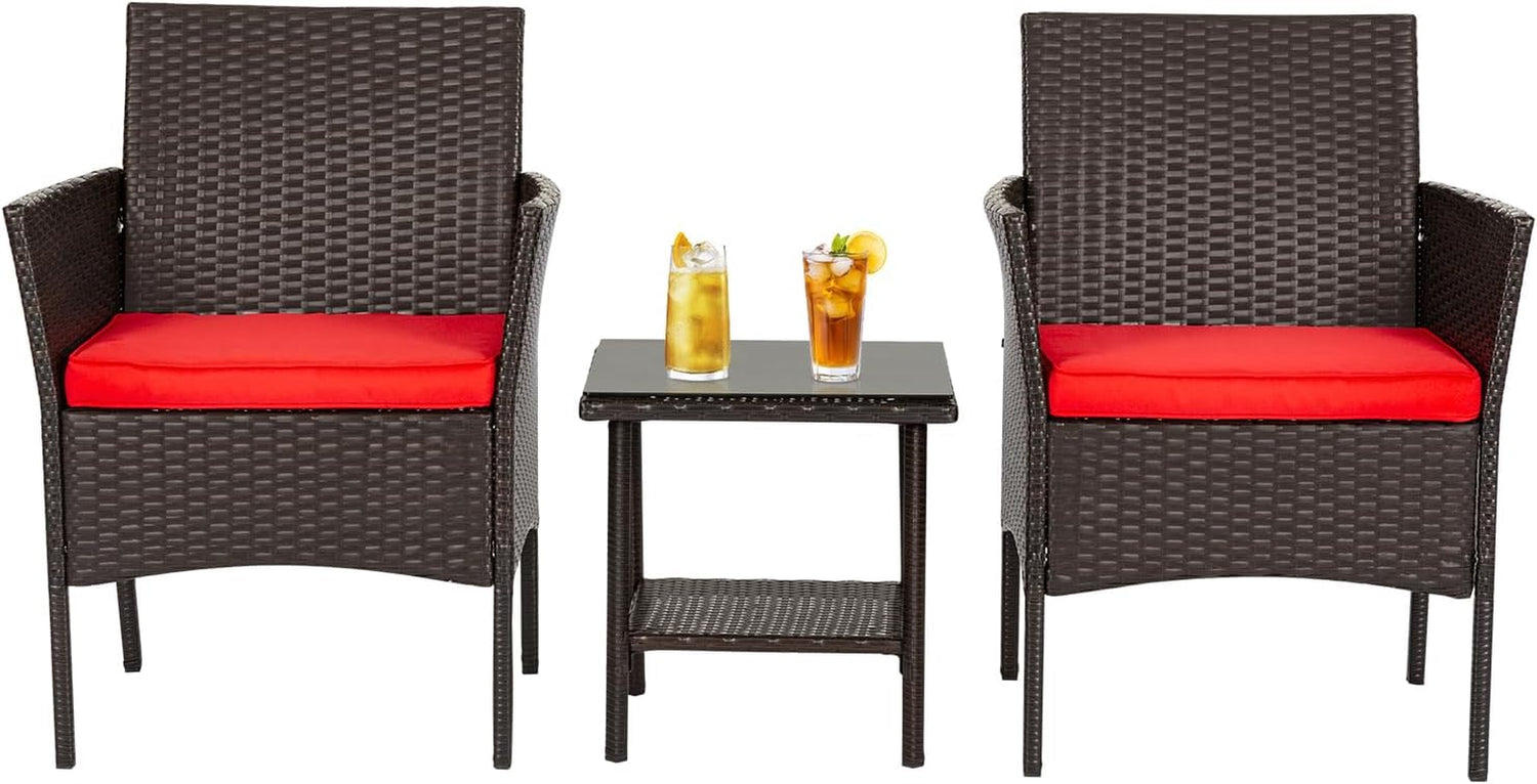 Pair of brown woven armchairs with red seat cushions separated by a small glass-top rattan side table with two drinks