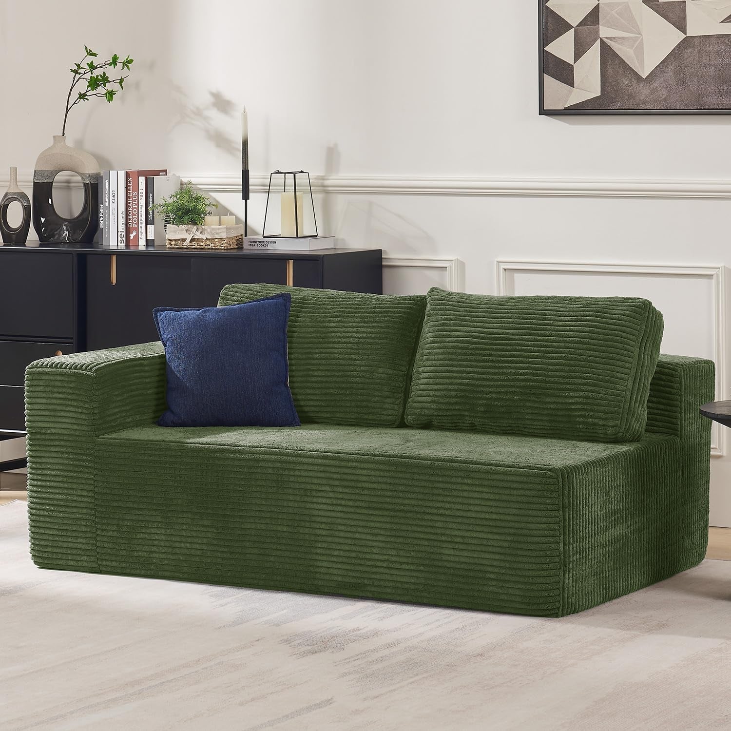 Close side view of the forest green corduroy loveseat module with a single blue throw pillow