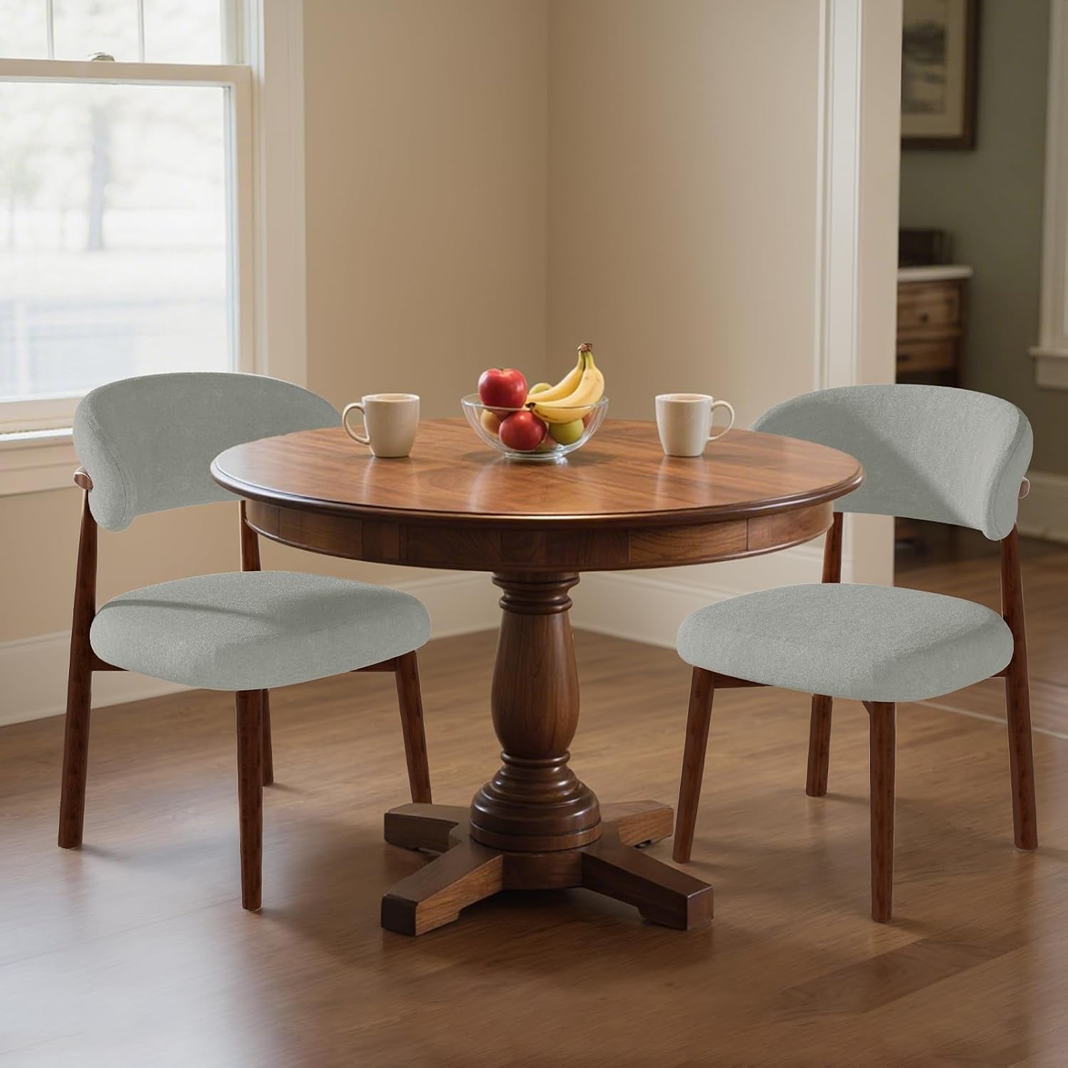 Two light gray curved-back dining chairs with brown frames sit at a round pedestal table.