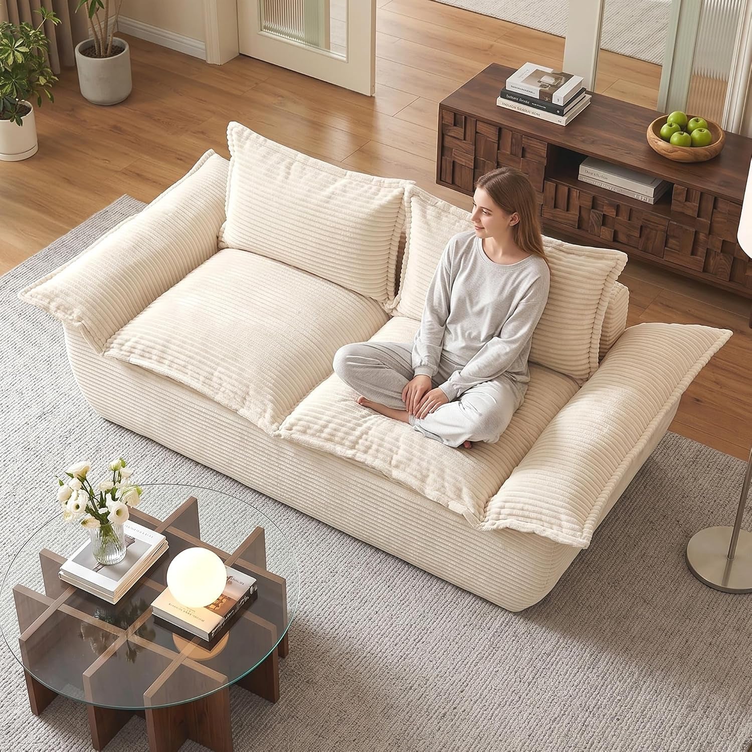 Beige corduroy 2-seater sofa angled top view with model seated in a living room