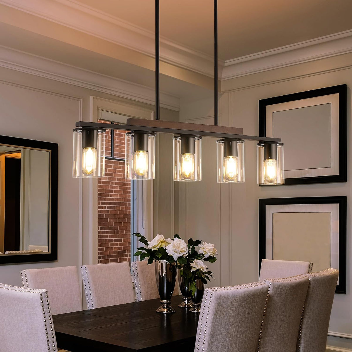 Five-light linear chandelier with clear cylindrical shades shown above a formal dining table, angled shot