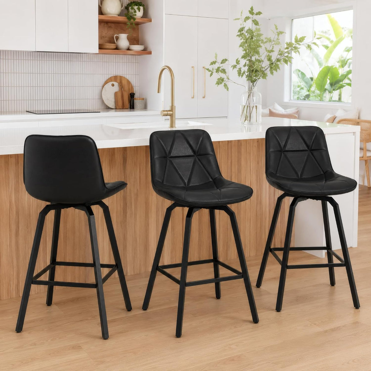 Three black faux‑leather swivel counter stools lined along a wood‑front island