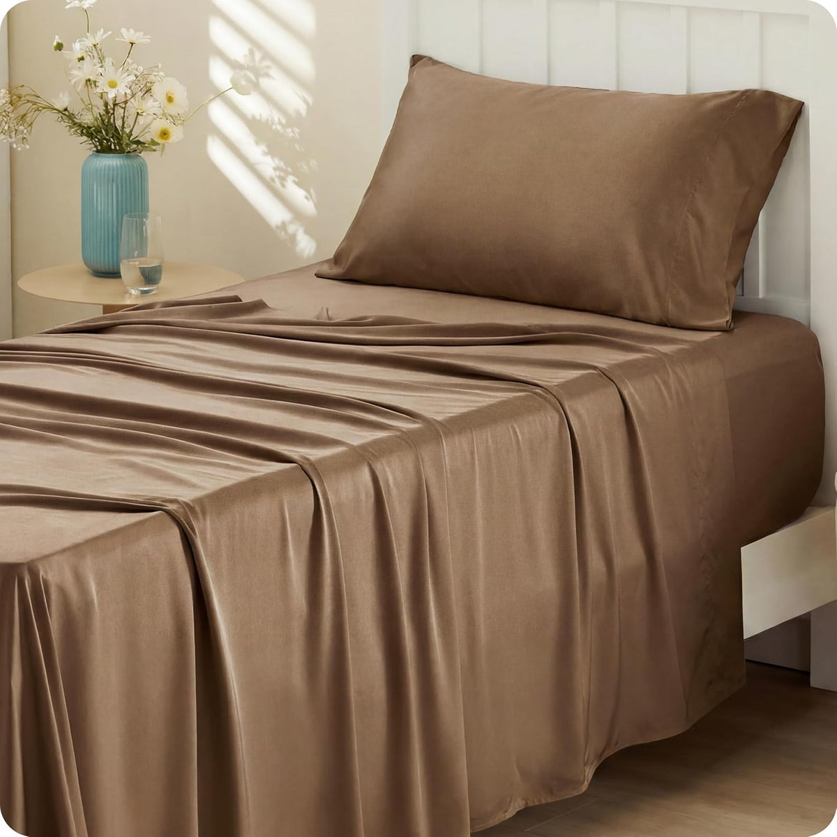Side-on shot of a bed made with warm brown silky sheets and a single pillow against a white slatted headboard.