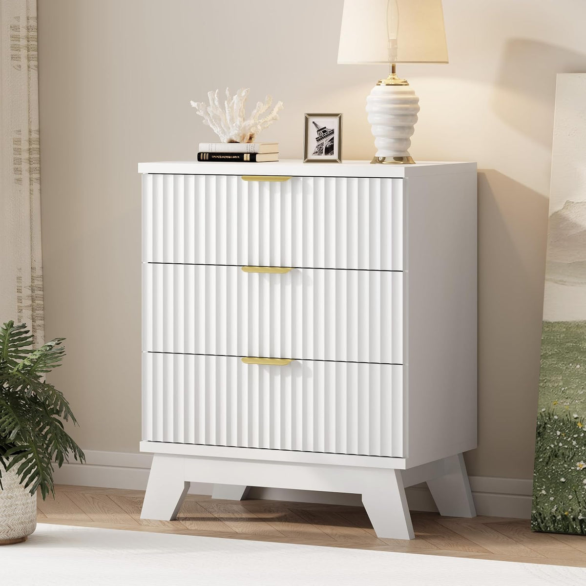 Three-drawer tall chest in white with fluted drawer fronts and gold handles, lamp on top.