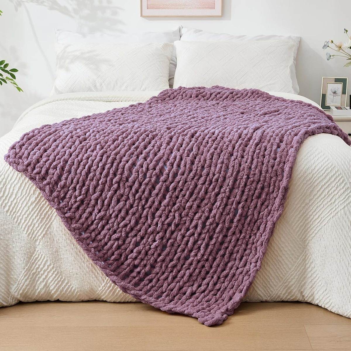 Bedroom scene with a mauve chunky knit throw draped over the foot of a white bed.