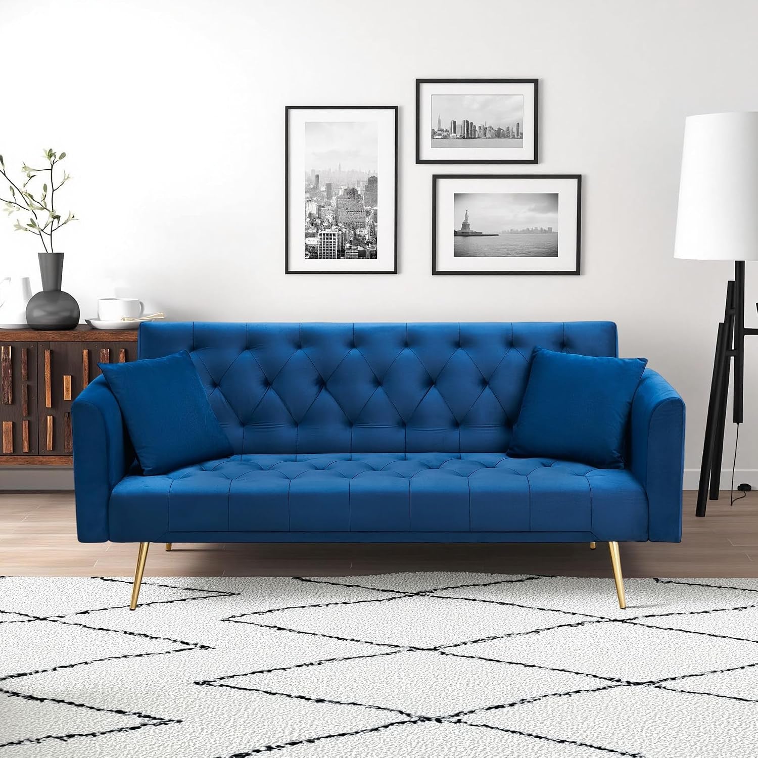 Straight-on view of a bright blue tufted velvet sofa with matching pillows and gold tapered legs.