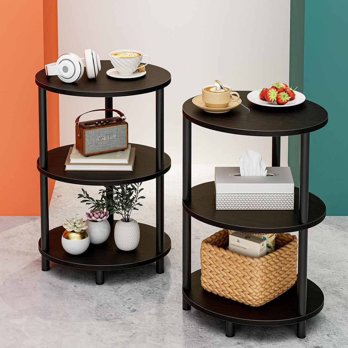 Two dark wood three-tier round end tables styled with cups, a basket, tissue box and decorative plants on a concrete floor.