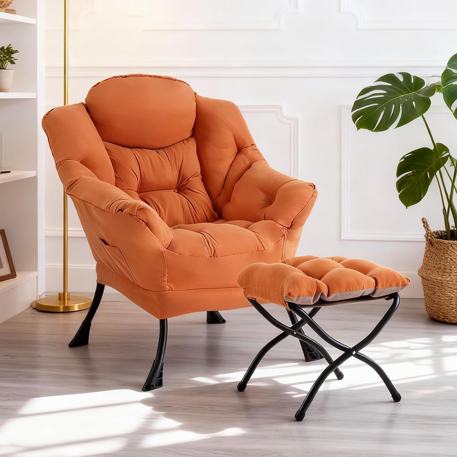 Bright room featuring an orange padded folding lounge chair with matching ottoman on black X‑frame legs.