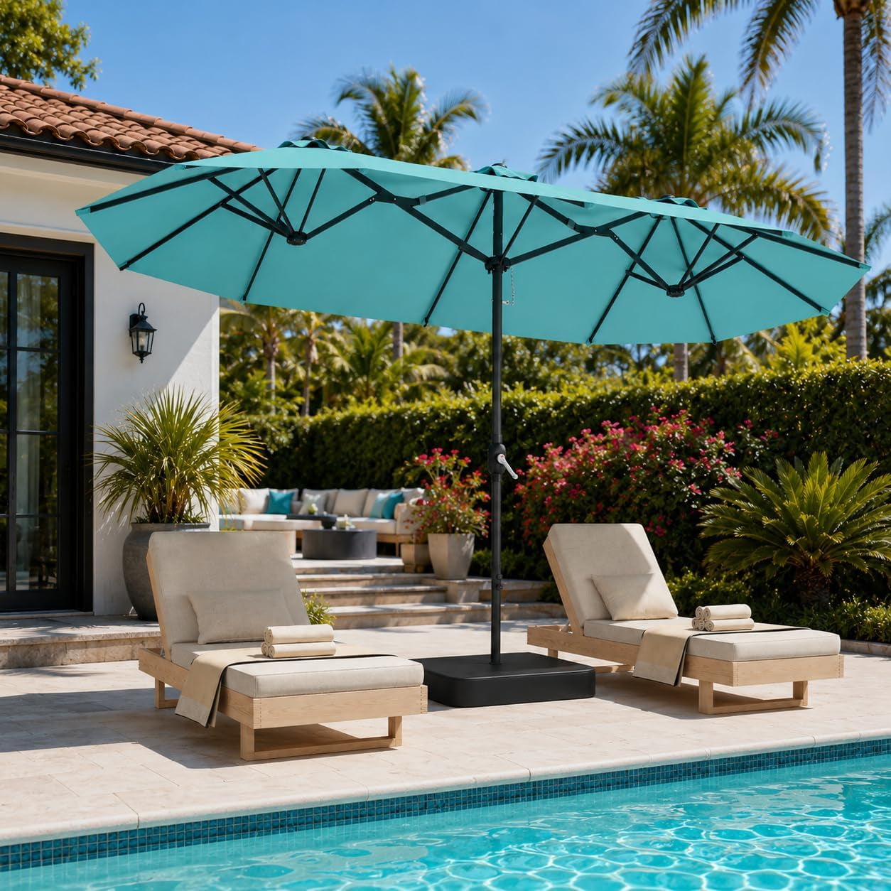 Poolside scene with a teal double-sided rectangular umbrella over two lounge chairs.