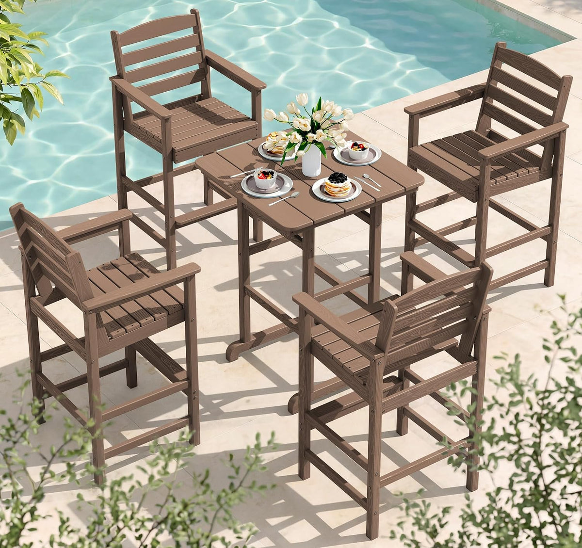 Light brown pub table set with four bar chairs arranged around a square tabletop near a pool, place settings on the table.