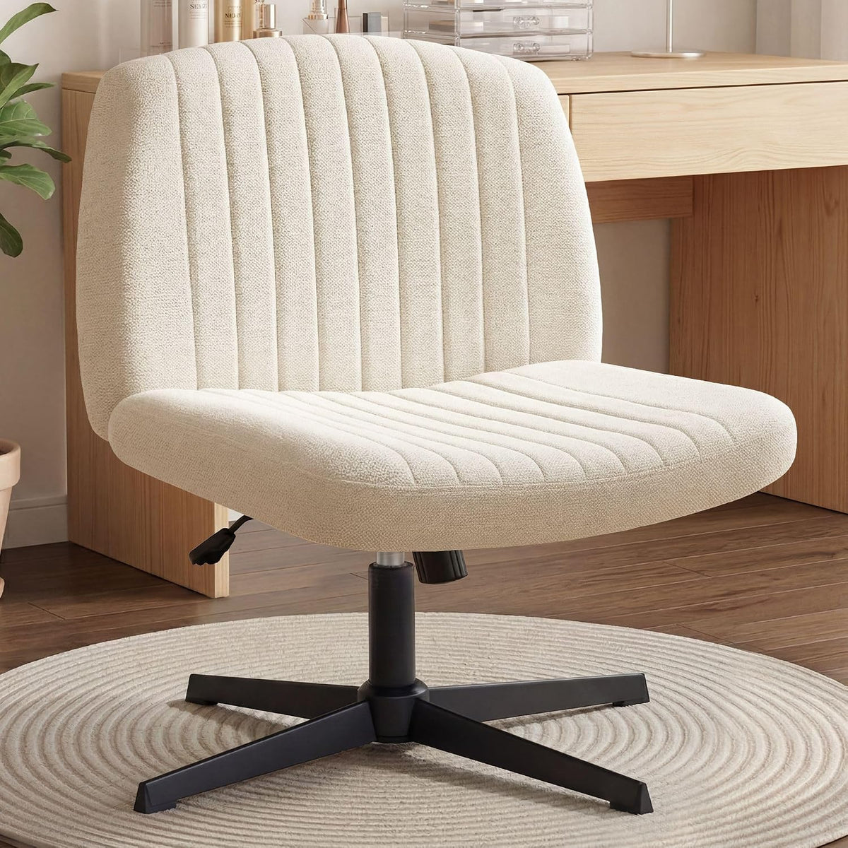 Cream-beige upholstered swivel desk chair with vertical channel tufting and black star base on round rug.