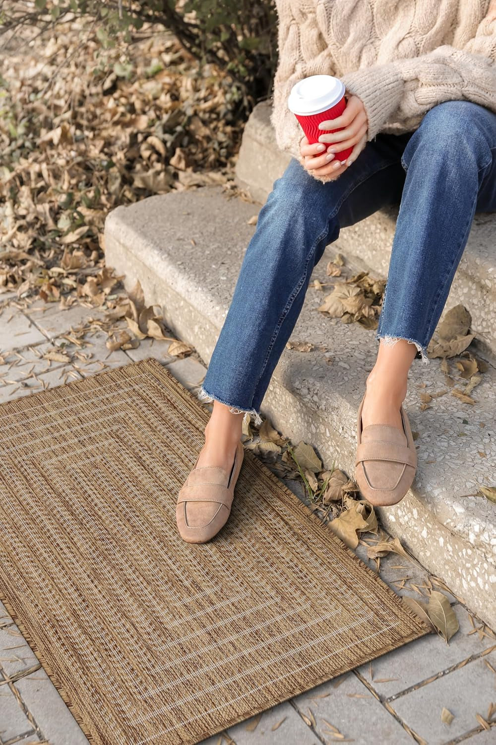 Small brown woven rug next to steps with a seated person wearing jeans and loafers