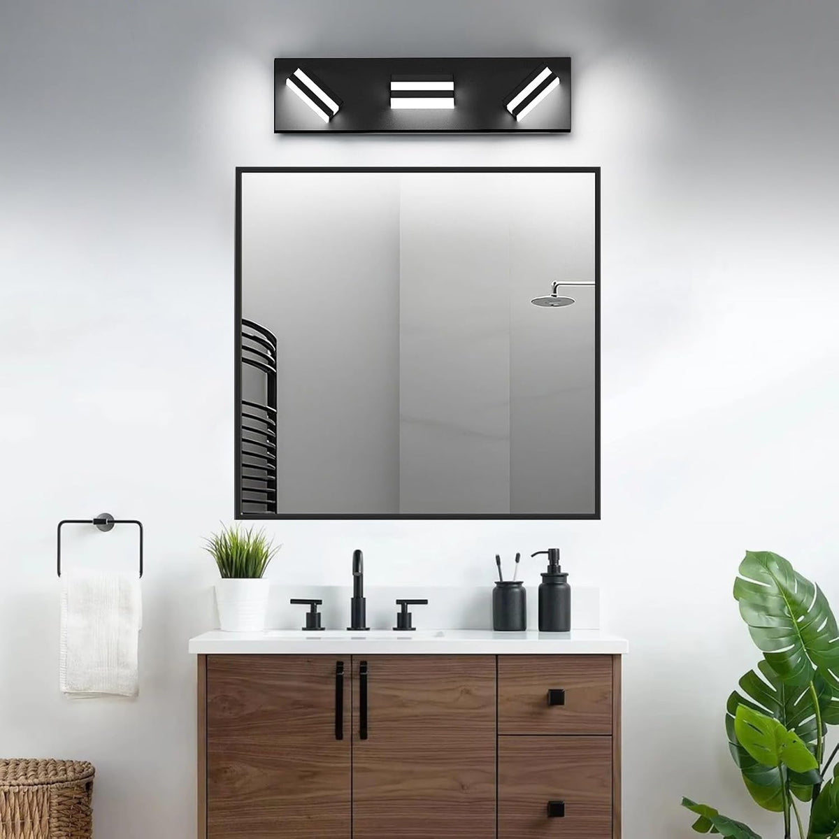 Modern vanity with square black-framed mirror, wood cabinet, black faucet and the LED three-light fixture mounted above.