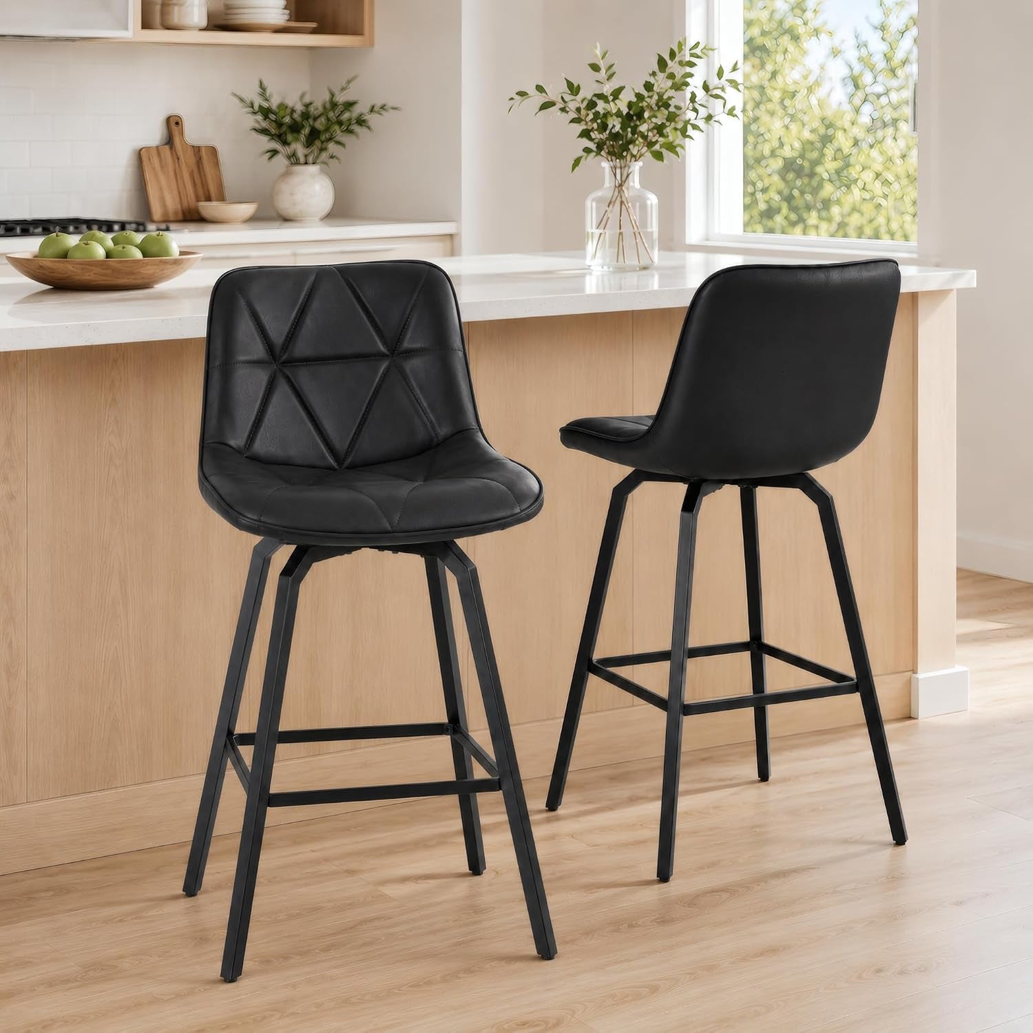 Two black faux-leather swivel counter stools with metal legs at a kitchen island