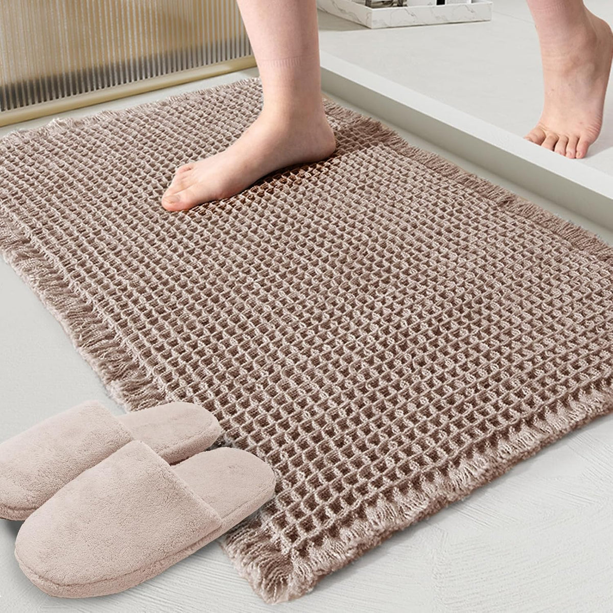 Taupe waffle bath mat beside slippers, with a person standing on it