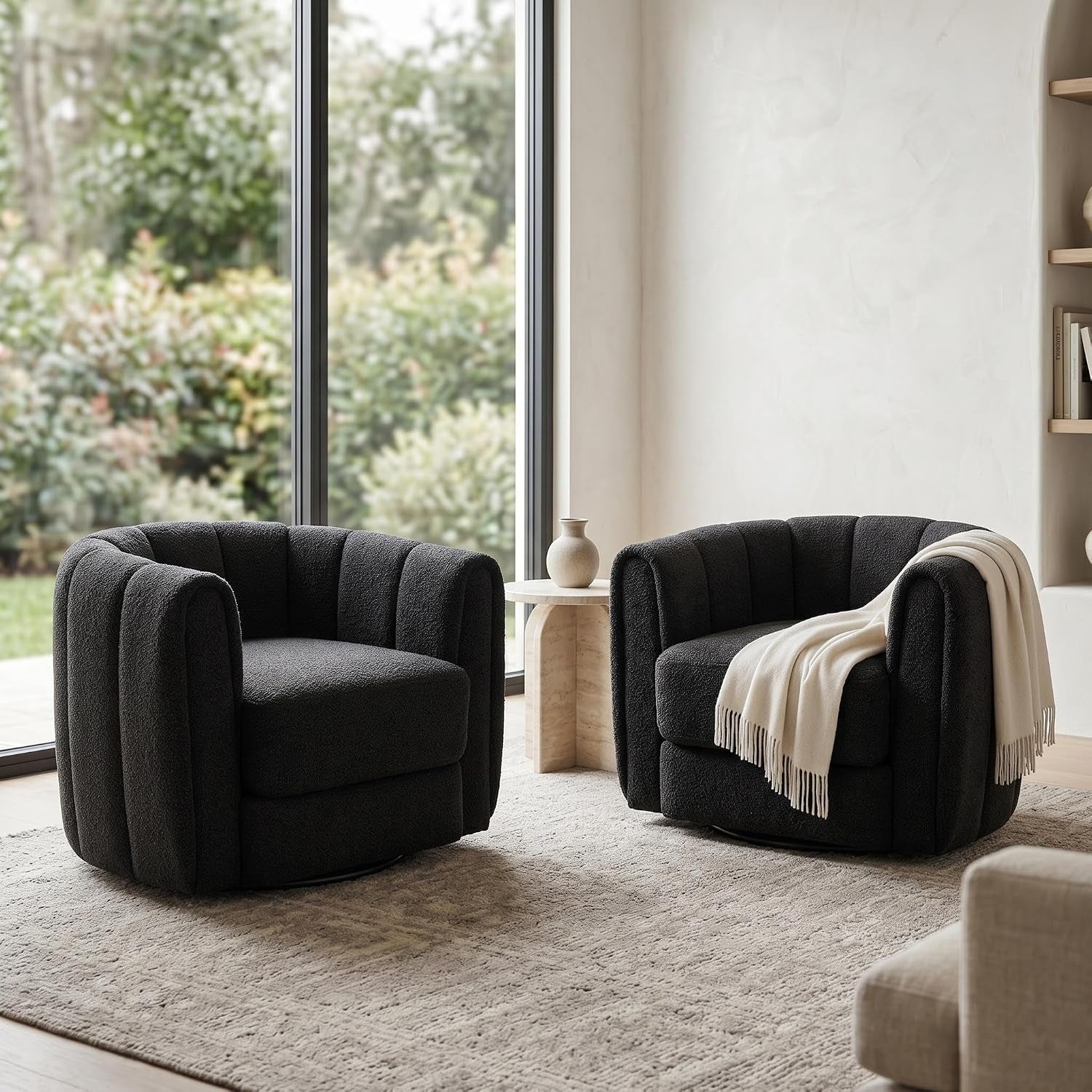 Two dark swivel barrel chairs arranged by tall windows with a small side table between them.