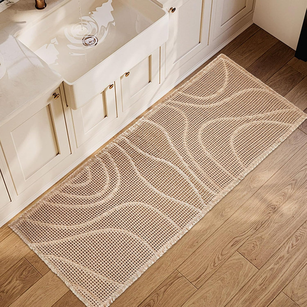 Beige rectangular wavy-texture mat placed on wood floor beside a white farmhouse sink.