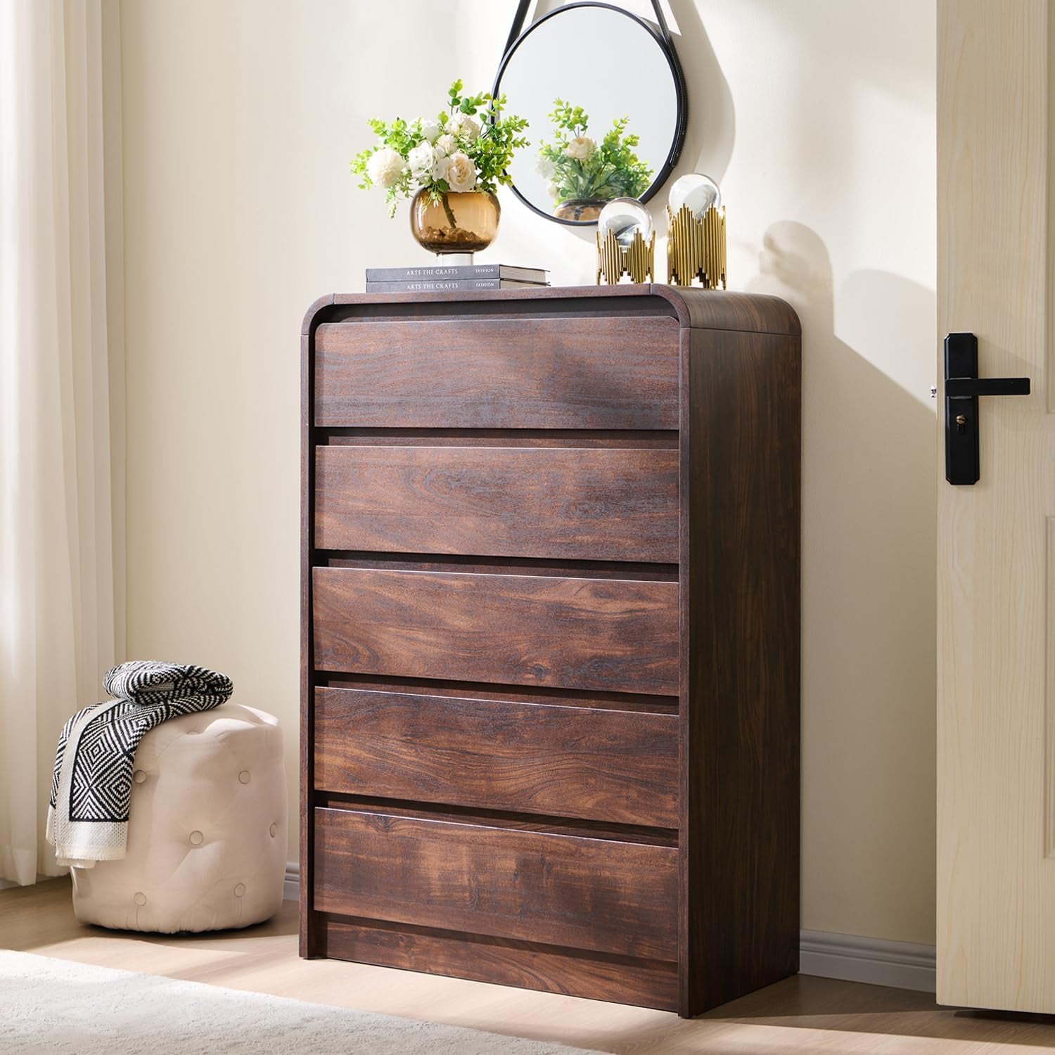 Tall seven-drawer dresser in a warm dark wood finish standing next to a door and pouf.