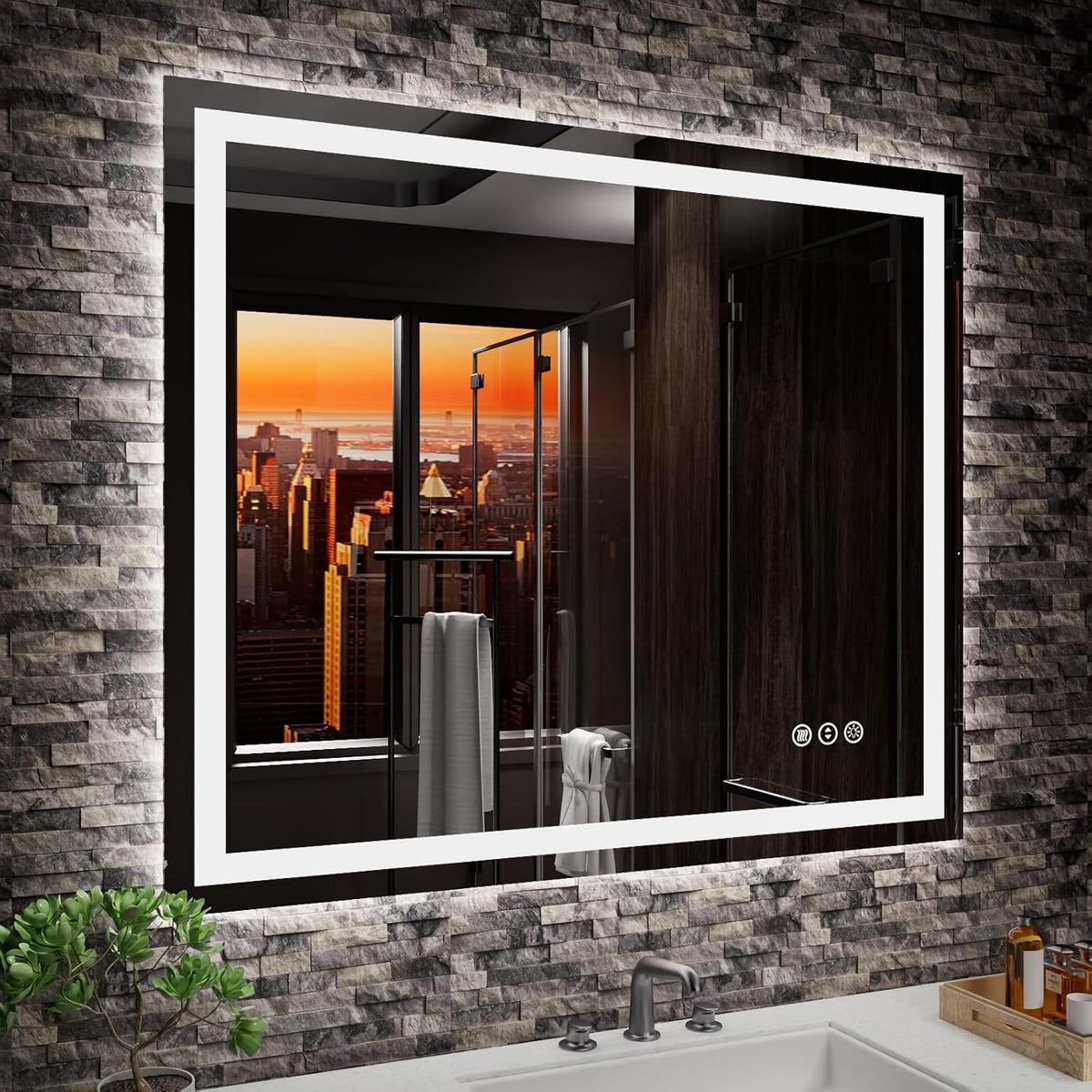 LED-framed mirror mounted on textured stone wall showing a sunset city skyline reflection and a glass shower door and towel