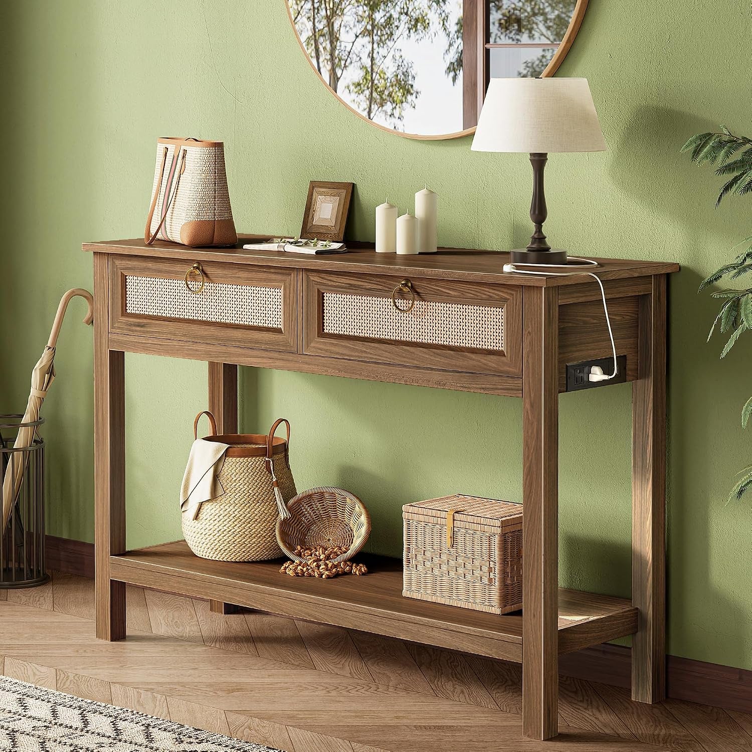 Angled front shot of a medium-brown rattan-front console table with two drawers, lower shelf, baskets and side power outlet.