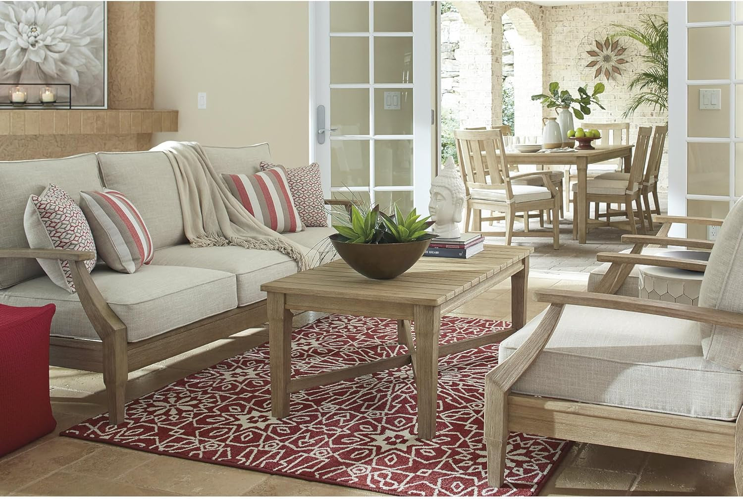 Indoor-outdoor styled room showing the three-seat sofa beside a coffee table and dining area beyond