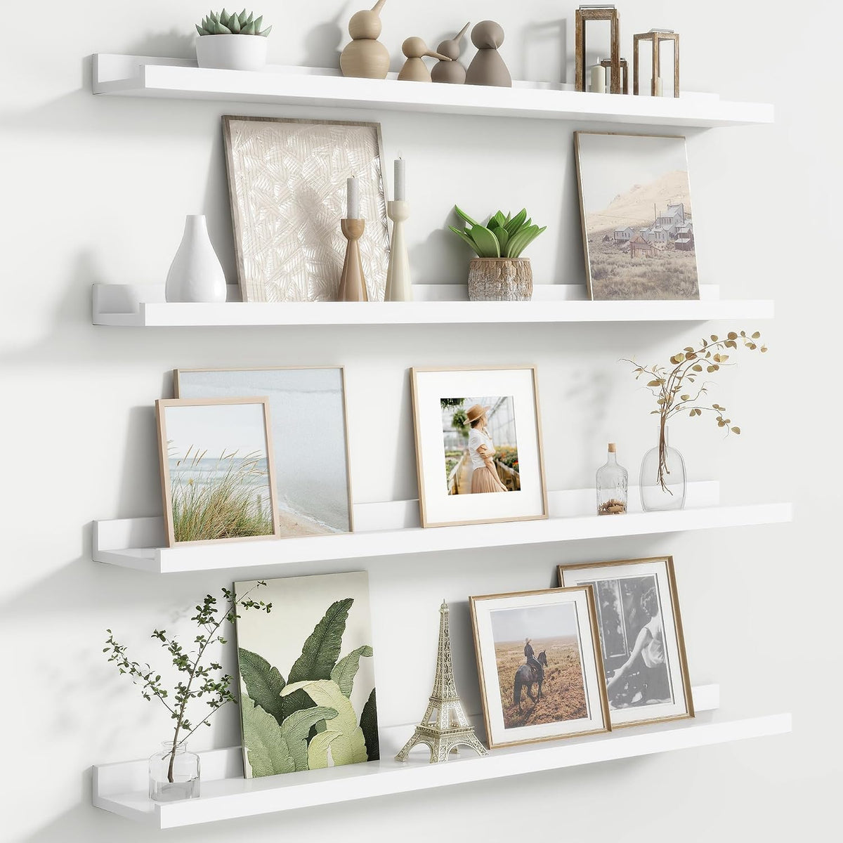 Three white floating picture ledges styled with vases, frames and small plants.