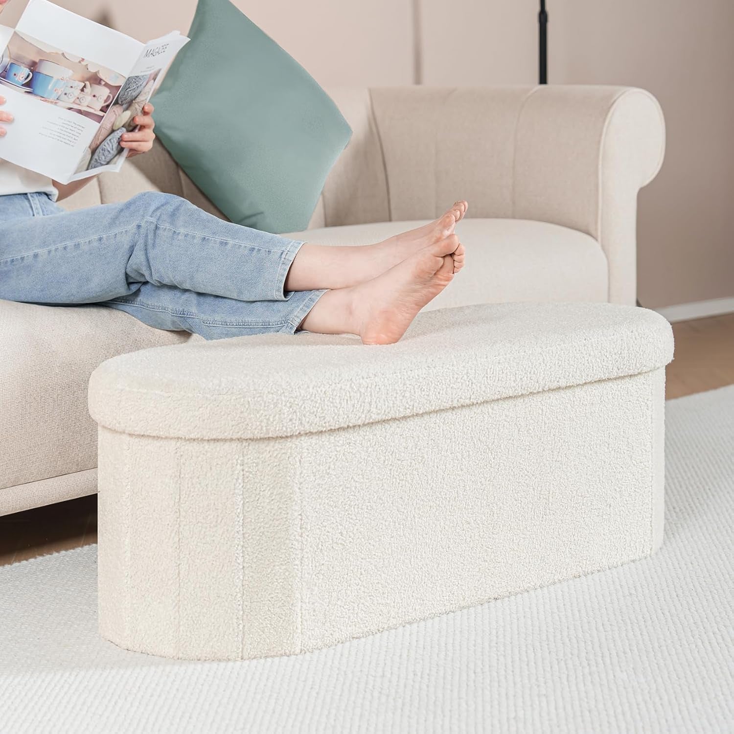 White sherpa ottoman used as footrest in front of a sofa in a living room scene