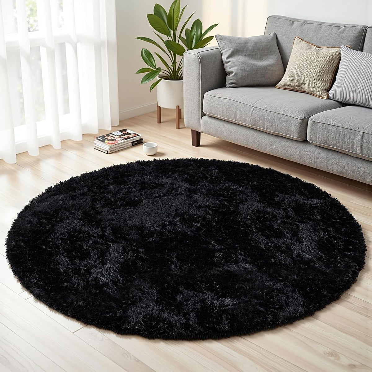 Round black shag rug placed on light wood floor in front of a gray sofa