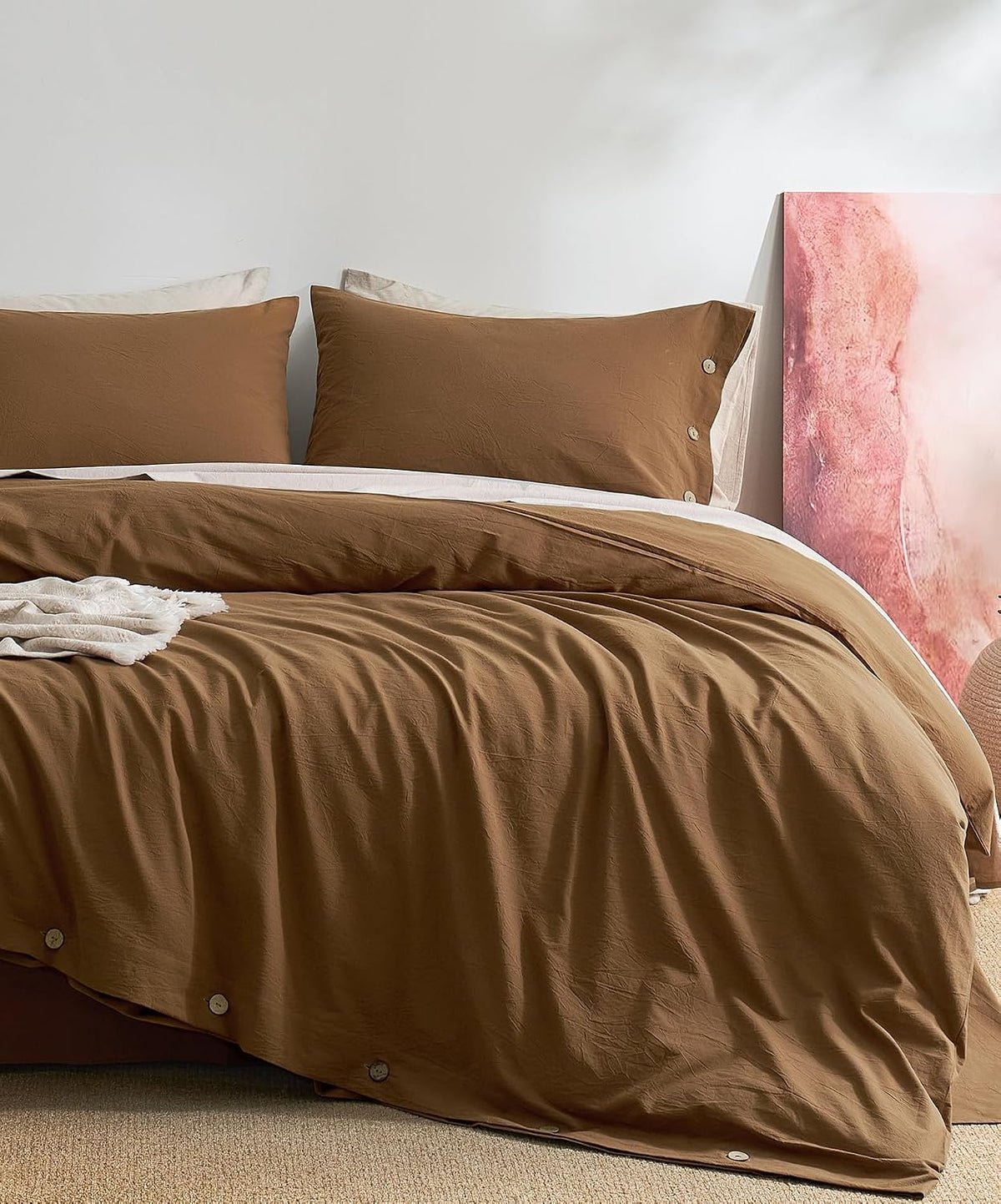Close front view of a bed with warm brown duvet cover and matching pillowcases, button details visible
