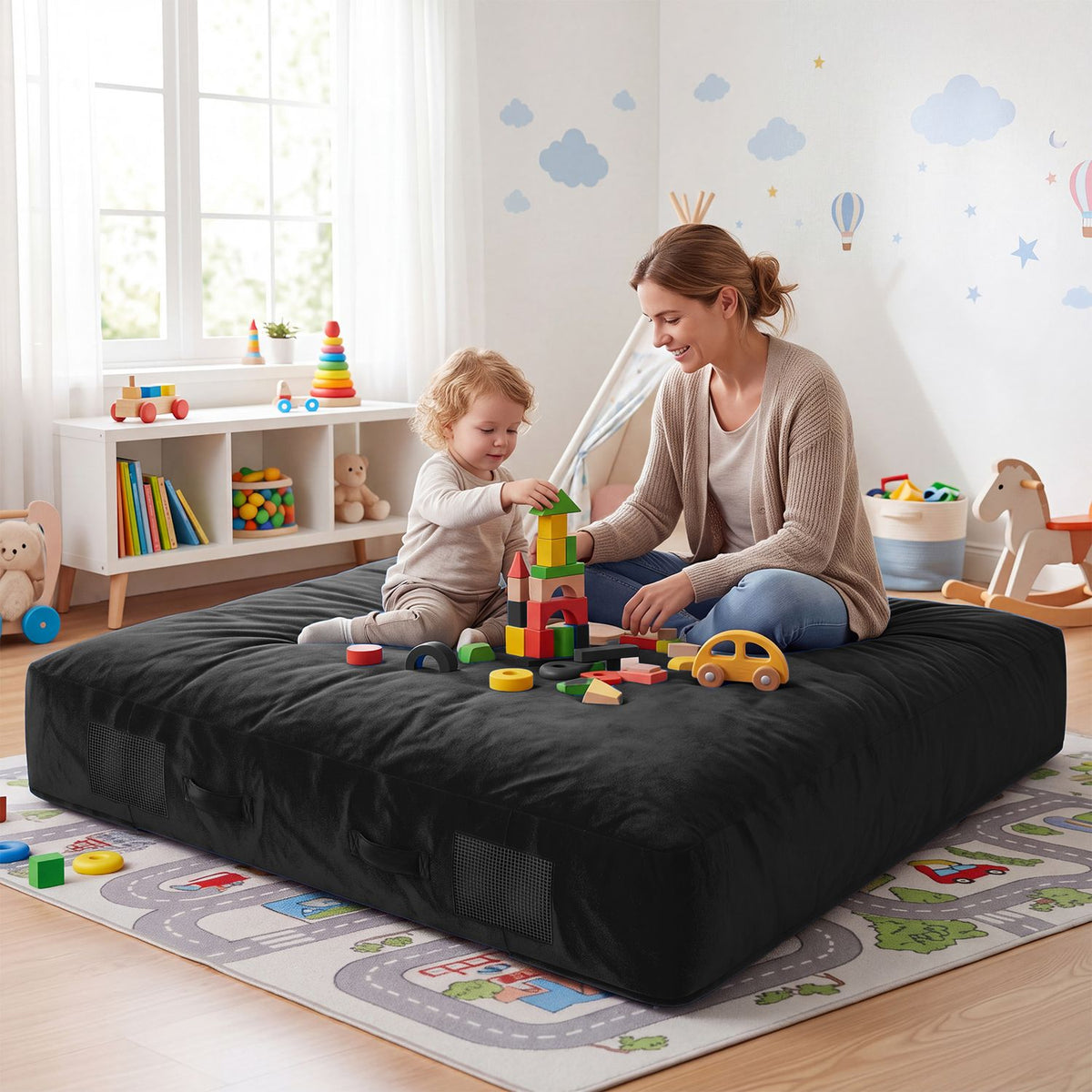 A child and adult play with blocks while seated on a black crash pad.