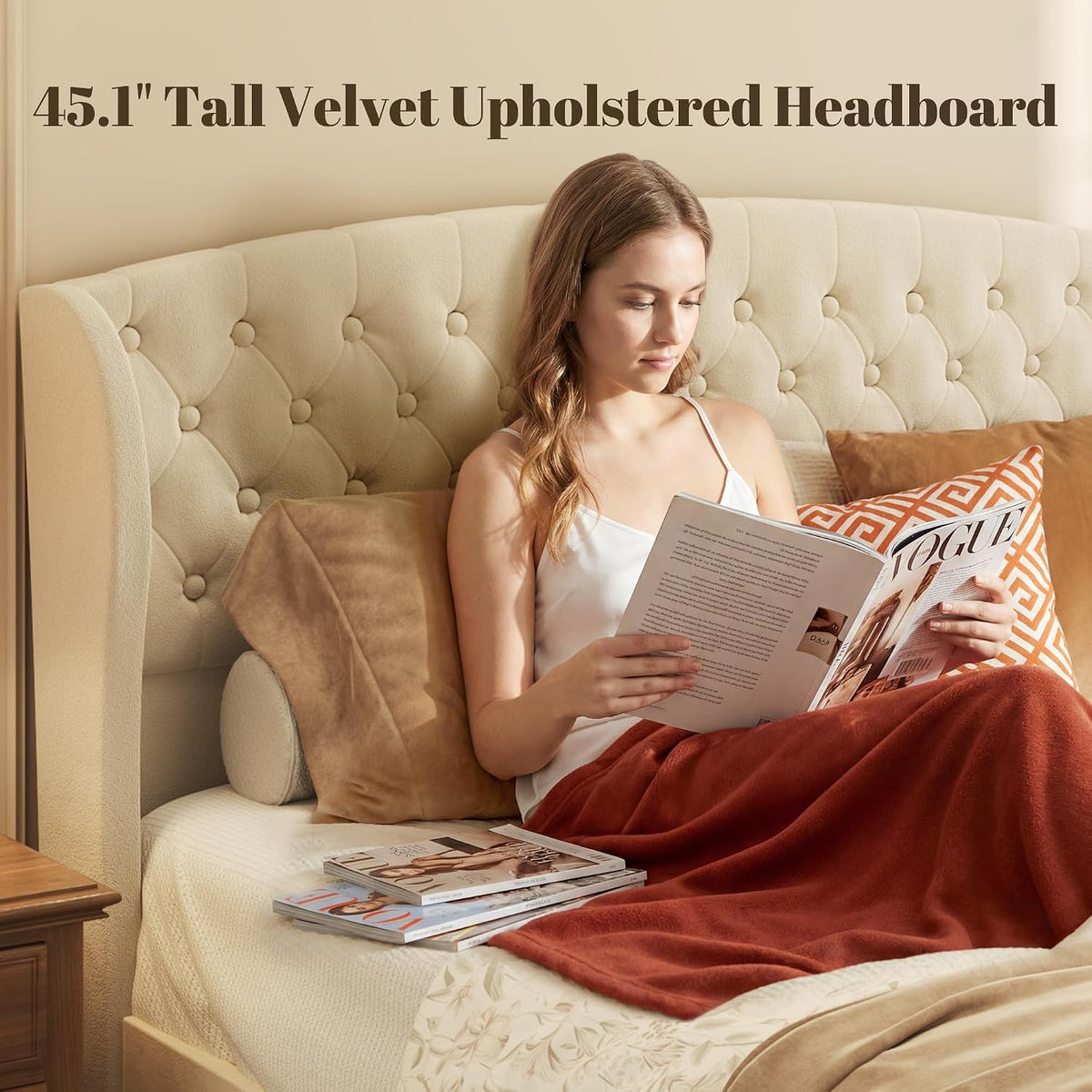 Close frontal view of the tufted diamond-pattern footboard and black tapered legs on the beige velvet bed