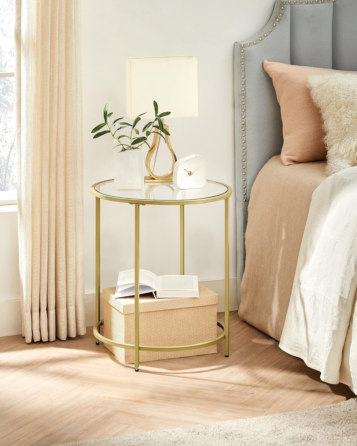Gold side table styled as a bedside table with lamp and decor in a bedroom setting