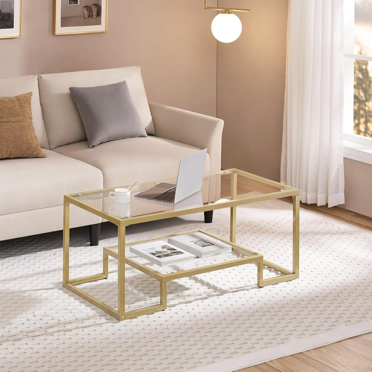 Gold metal-framed glass coffee table front-left view in living room setting with beige sofa