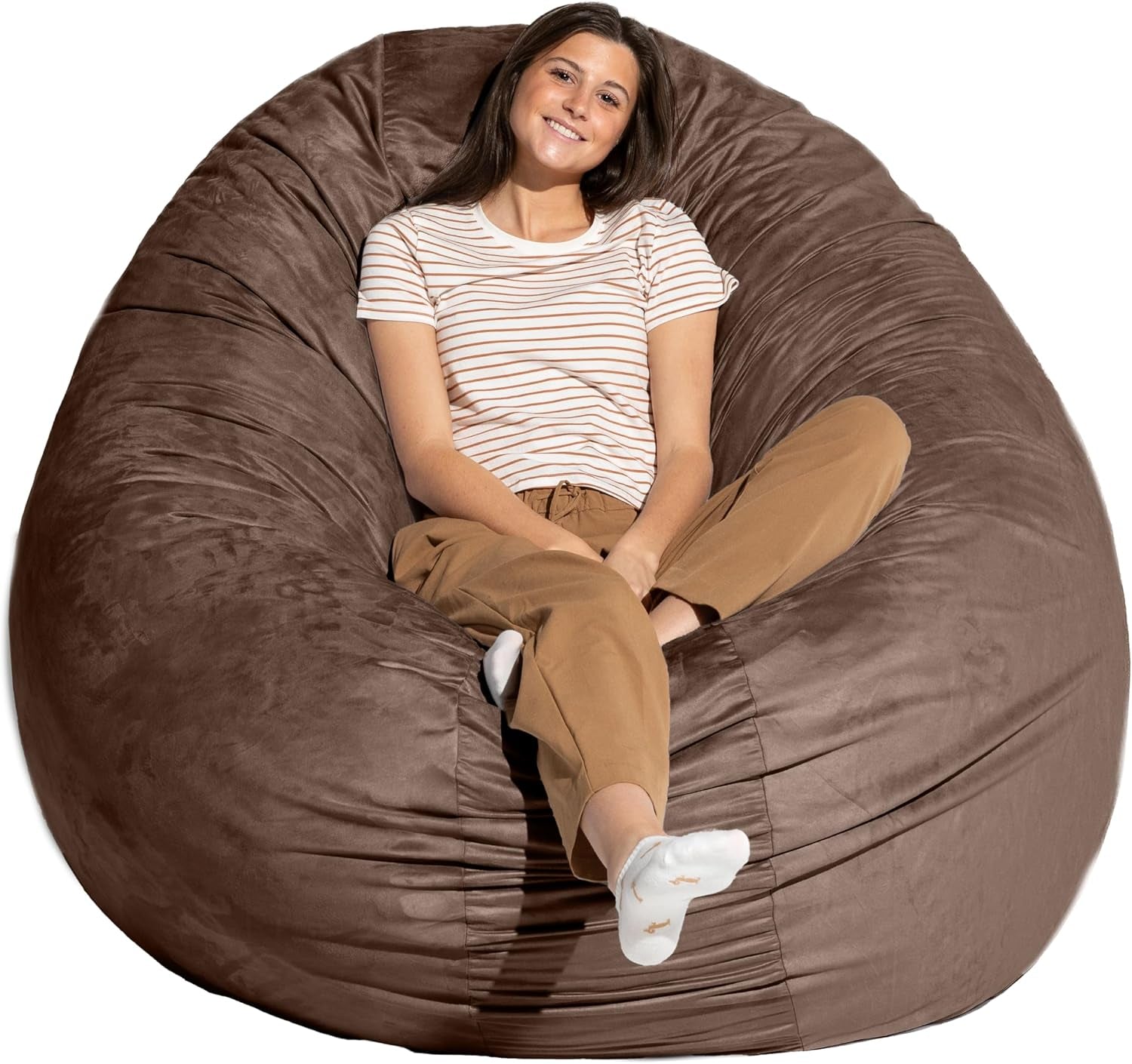 Woman reclining in a large chocolate-brown cocoon bean bag chair, legs crossed and smiling