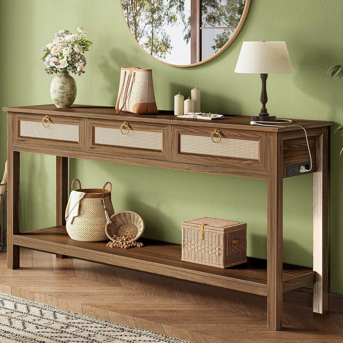 Angled view of the three-drawer rattan console with a lower shelf holding woven baskets and decor against a green wall.