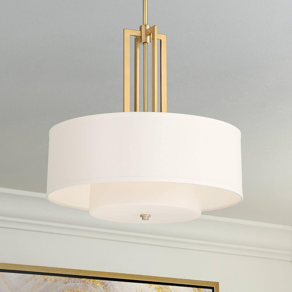 Gold metal drum pendant with off-white linen outer shade angled front view on ceiling