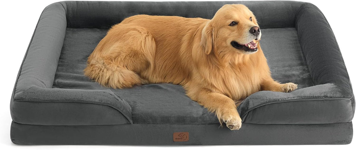 Angled overhead shot of a golden retriever lying across a charcoal-gray bolster bed, head turned to the right.