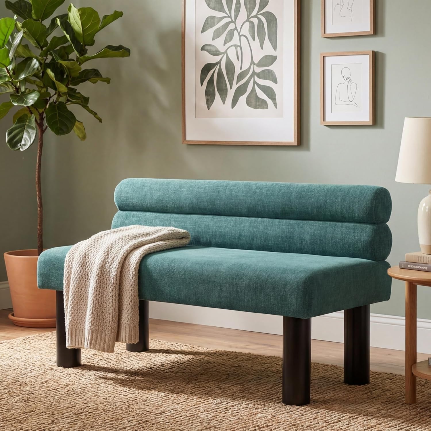 Teal upholstered armless bench with round dark legs styled in a living room scene.