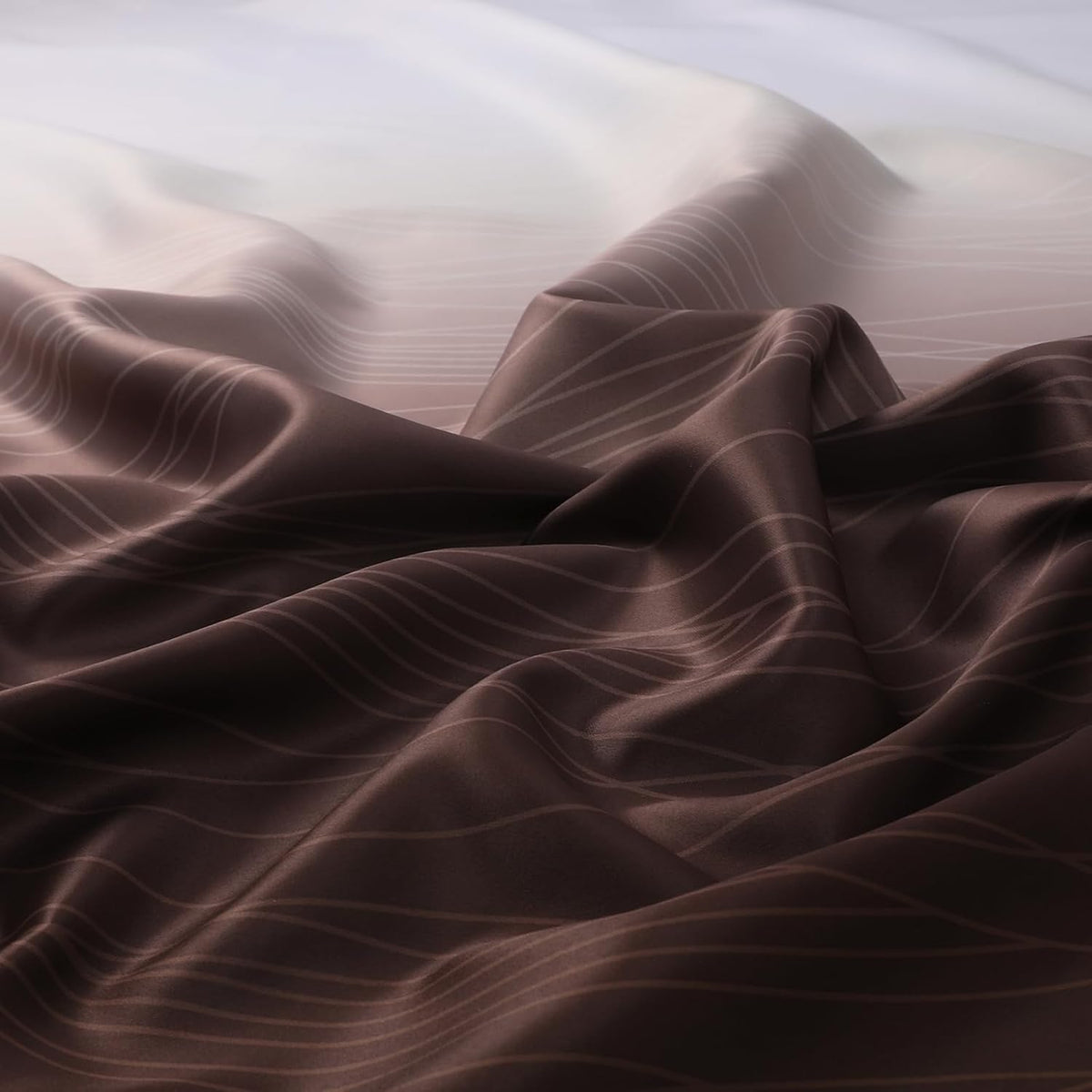 Close-up of draped ombre fabric showing brown to light gradient with wavy stripe pattern.