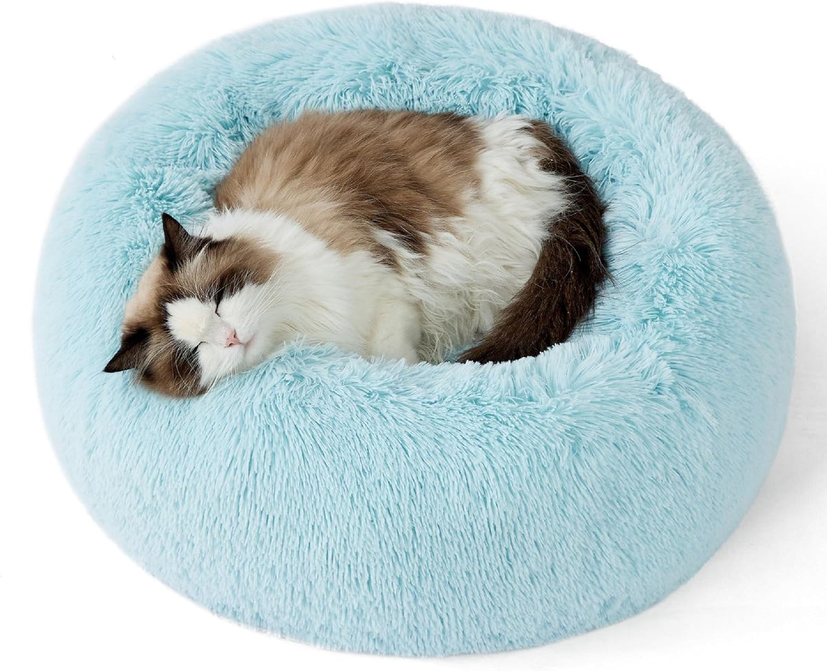 Top-down view of a light blue round faux-fur donut pet bed with a sleeping longhaired cat.
